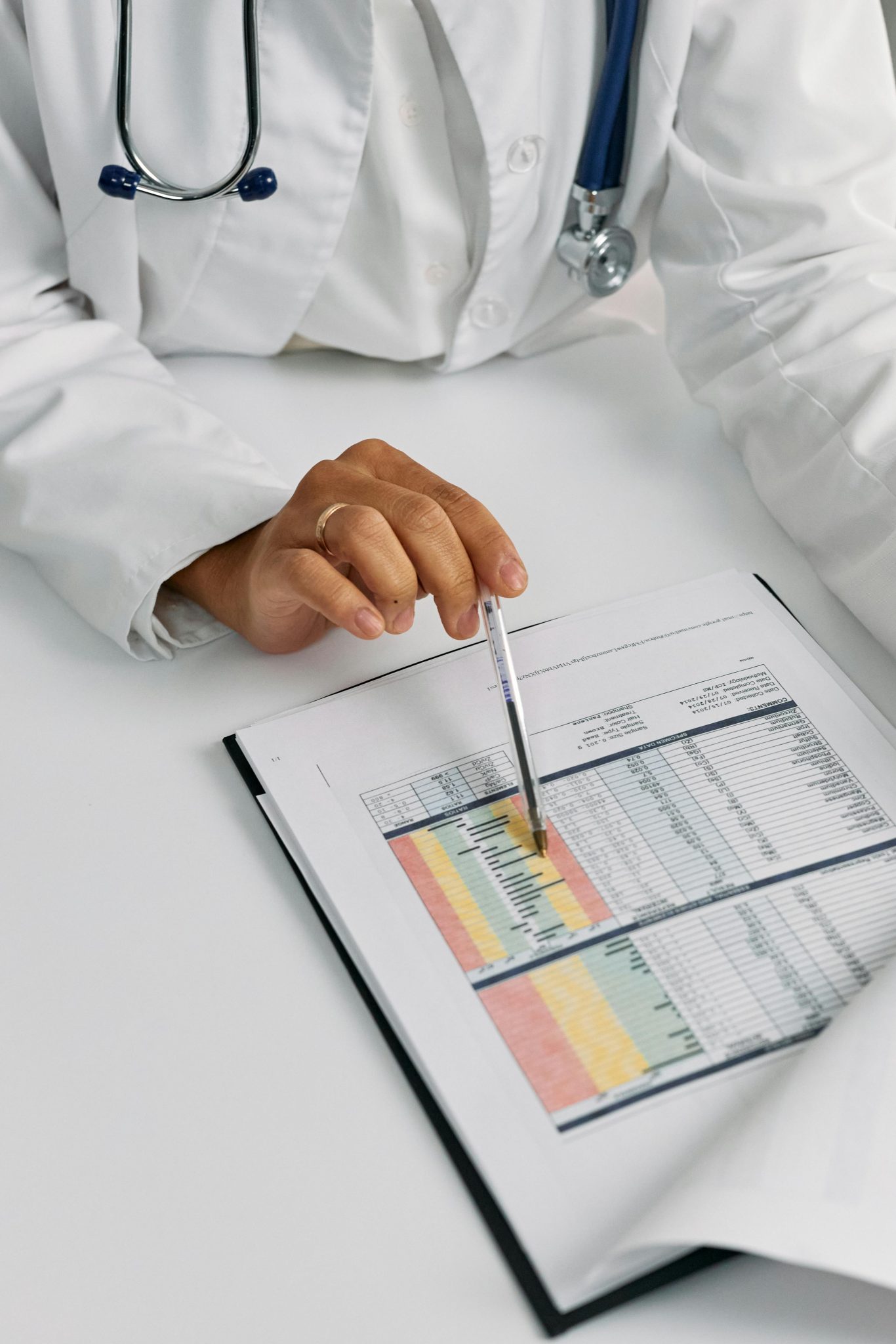 Doctor analyzing patient charts with a pen, focusing on data points for medical insights.